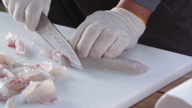 Slicing raw fish delicately with a knife on a cutting board