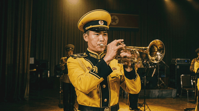 Musician wearing yellow North Korean uniform playing trumpet