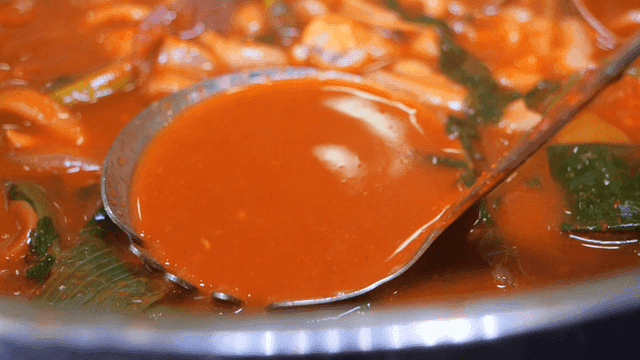 Rich squid kalguksu broth served in ladle