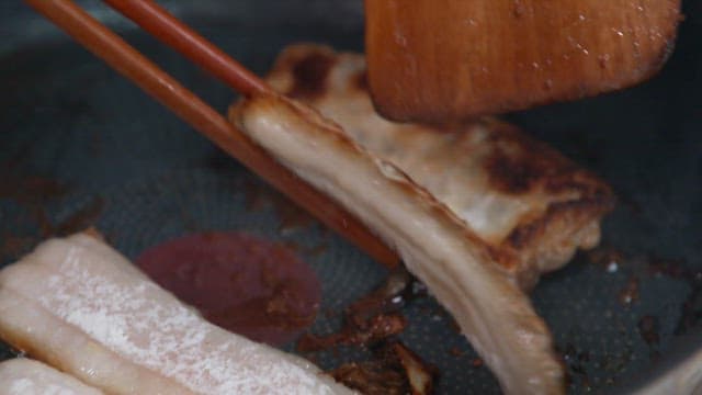 Grilling hairtail with chopsticks in a frying pan