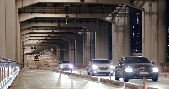 Vehicles passing by Bridge with lights on