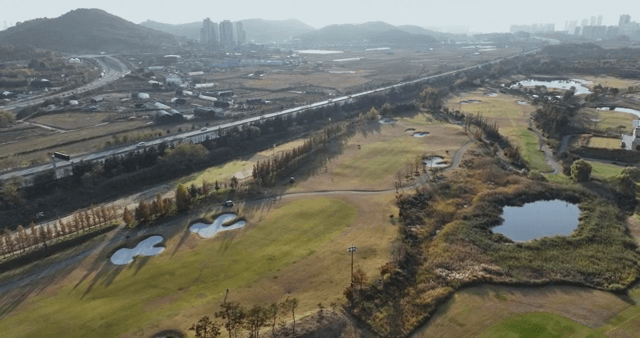 A golf course with surrounding cityscape