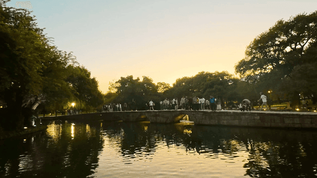 저녁 연못 위 돌다리 위를 걸어 다니는 사람들