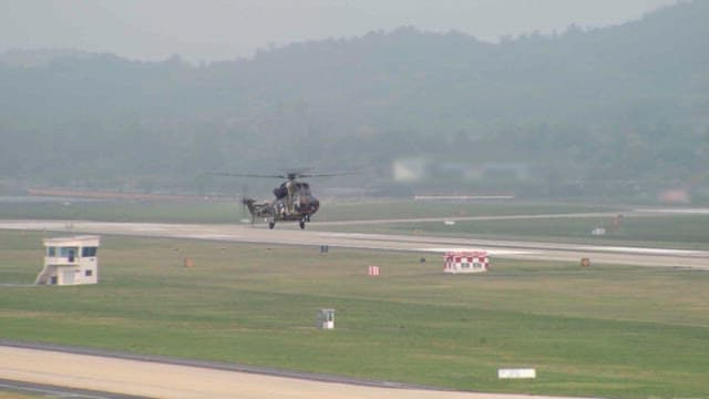 Military helicopter landing on a runway in the misty morning