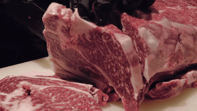 마블링이 있는 큰 소고기 덩어리를 자르는 모습