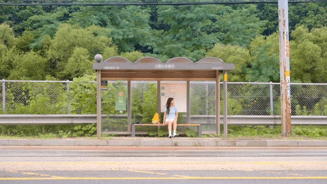 시골의 버스 정류장에서 기다리는 여성