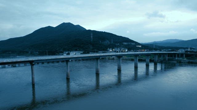 도시 스카이라인이 보이는 강 위의 자동차들이 지나가는 다리