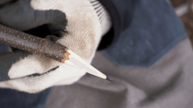 깎은 나뭇가지 연필을 들고 있는 손