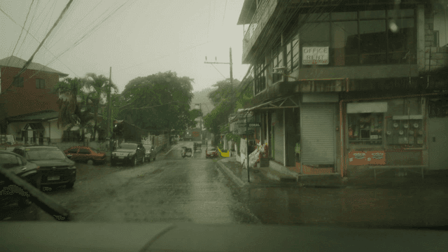 Passenger seat view of car driving down street on rainy day