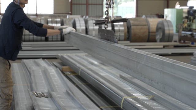 Workers handling metal beams in a factory