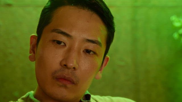 초록색 조명 실내에서 주변을 둘러보는 남자