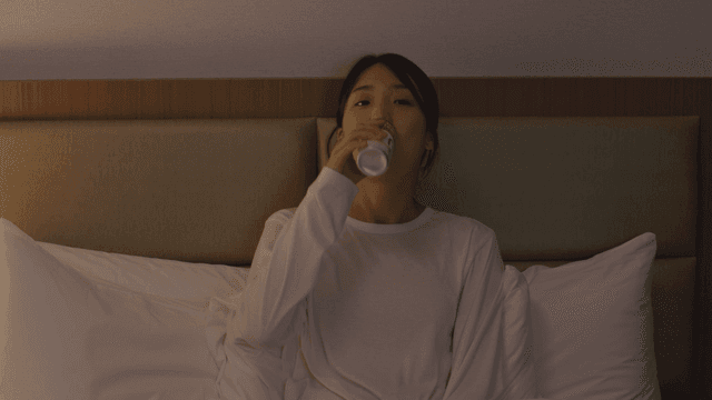 Woman sitting on bed drinking a can coffee