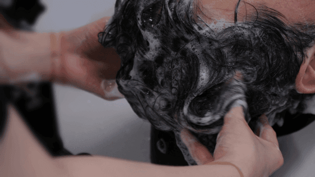 Hairdresser massaging hair while shampooing it at beauty salon