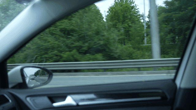 Driving on a highway with green trees