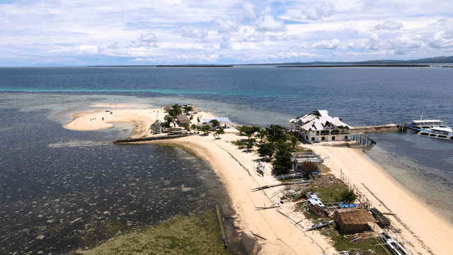 Small island with sandy beach and buildings.