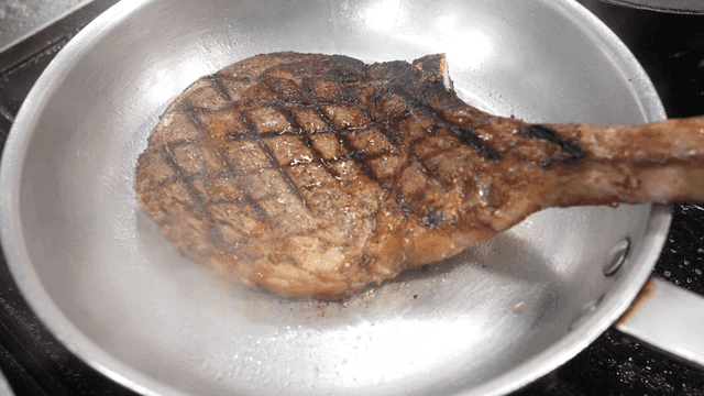 Steak being cooked in a hot pan