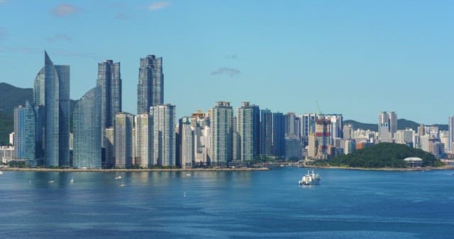 Busan, a modern city with high-rise buildings and calm, blue sea with boats