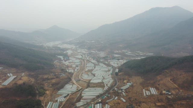 Rural mountainous area with many greenhouses on a foggy day