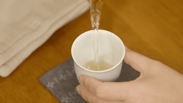 Pouring tea into a white cup on a table