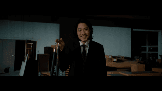 Man in a suit holding nunchaku indoors