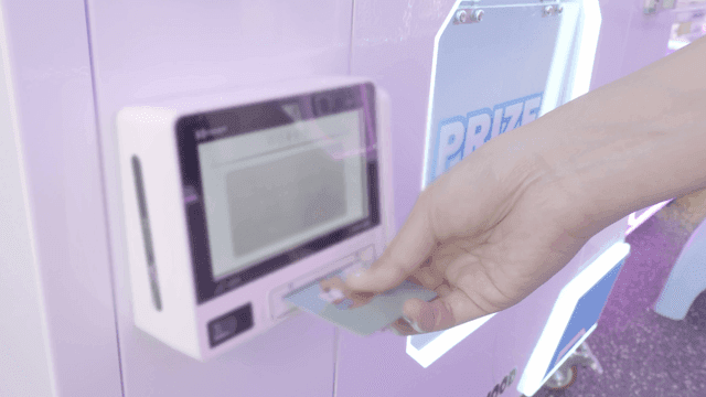 사람이 가챠샵 뽑기 자판기에서 카드를 사용하는 모습