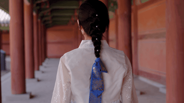 Woman in hanbok walking in a traditional corridor