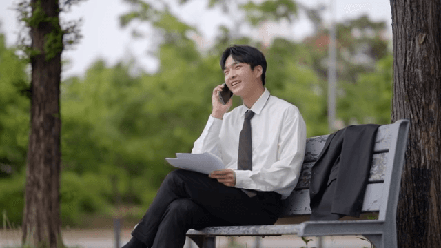 Office worker man reading documents and talking on the phone on a bench