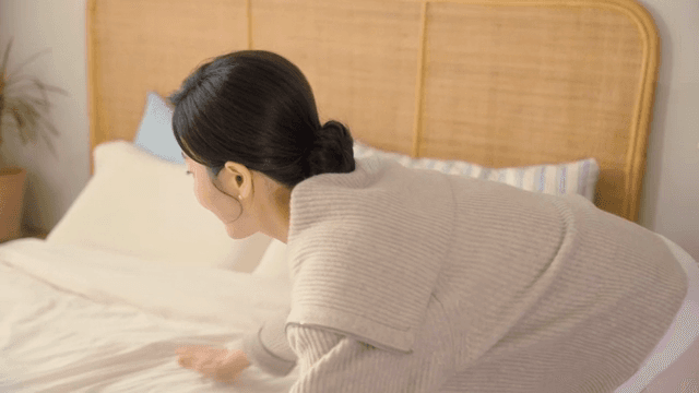 아늑한 방에서 침대를 정리하는 여성