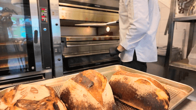 갓 구운 빵을 오븐에서 꺼내는 제빵사