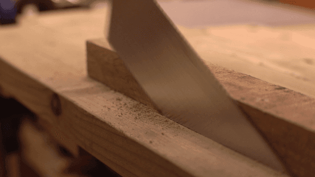 작업대에서 톱으로 나무를 자르는 모습