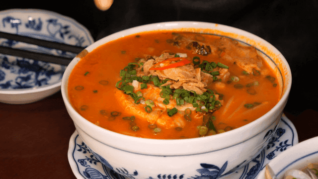 Bowl of spicy chicken rice noodles on table