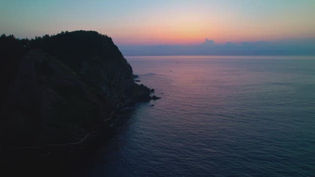 Sunset over a calm ocean and cliff