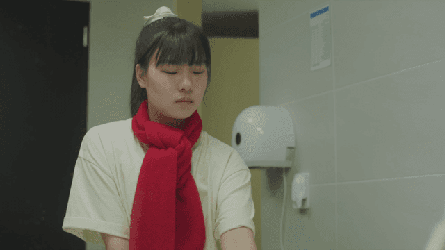 Young woman wearing a scarf washing her hands in the bathroom