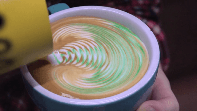 Colorful latte art being created on a coffee cup