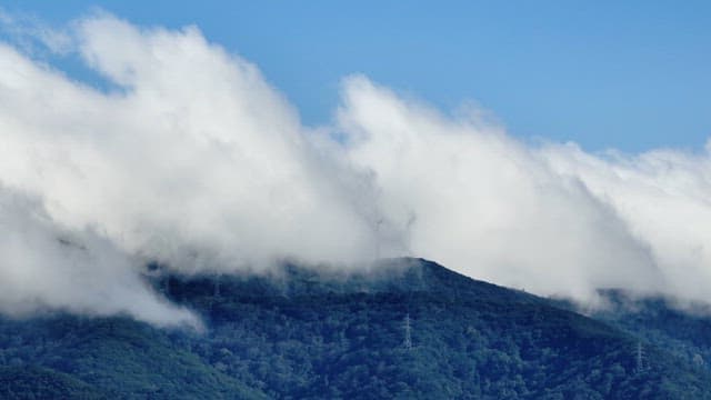 Clouds drifting over a lush mountain