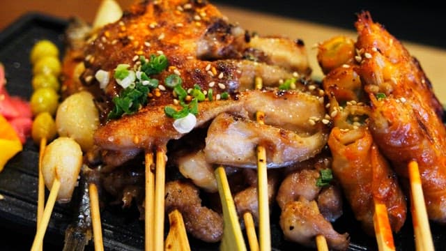 Various types of grilled skewers neatly arranged on an iron plate