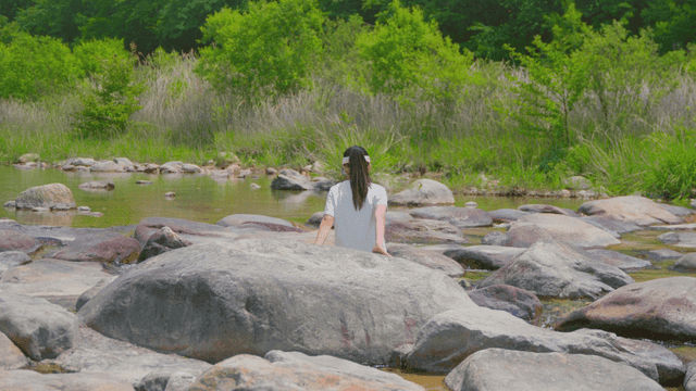 강가의 바위에 앉아 있는 소녀