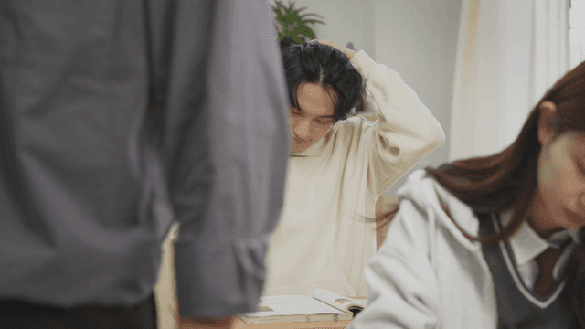 교실에서 졸고 있는 학생을 웃으며 깨우는 선생님