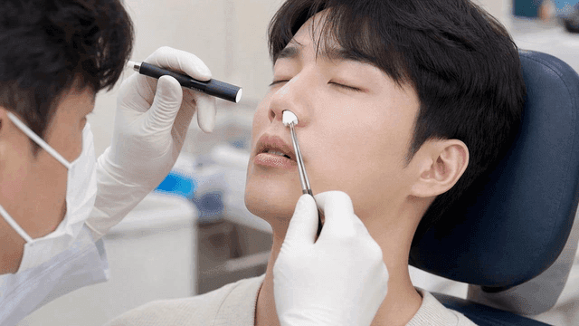 Doctor disinfecting patient's nose