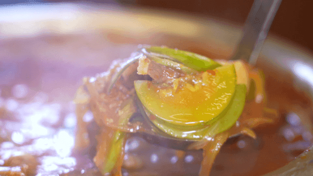 Ladle for scooping out zucchini gochujang stew containing vegetables and meat