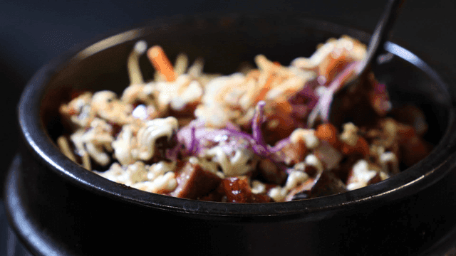Spoon mixing oven-baked spicy pork trotters with vegetables and sauce