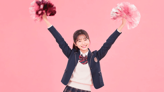 Cheerful female student holding pom-pom