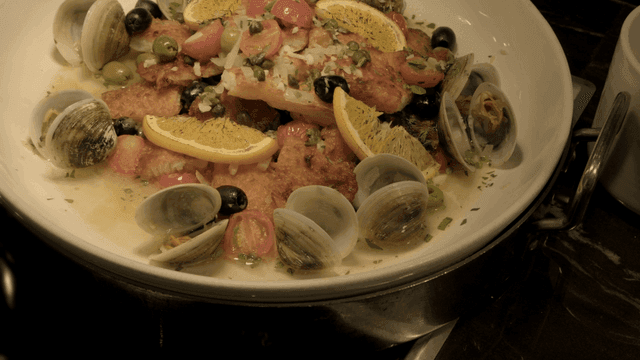 Italian steamed fish with clams and lemon wedges