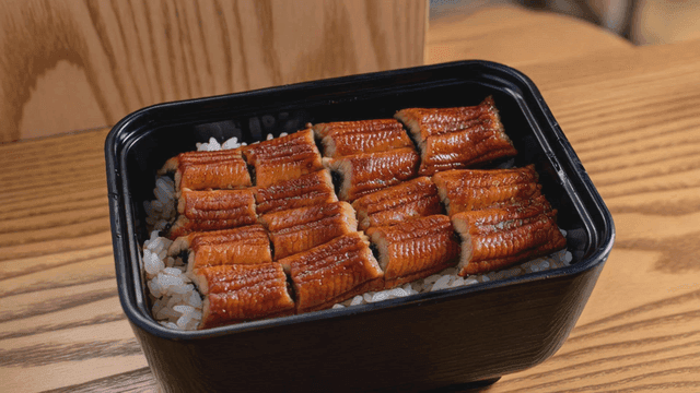 Grilled eel on rice in a black container