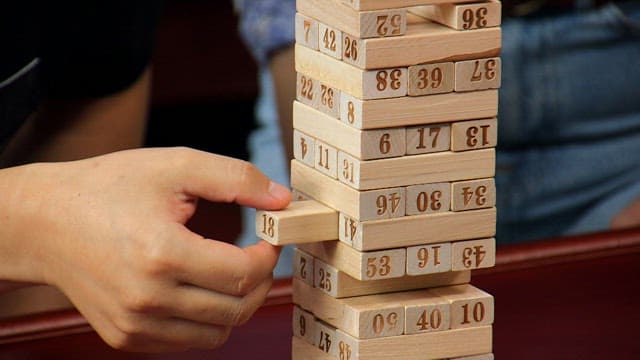 테이블 위에서 젠가 블록 하나를 빼는 손