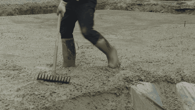Worker leveling wet concrete with a rake