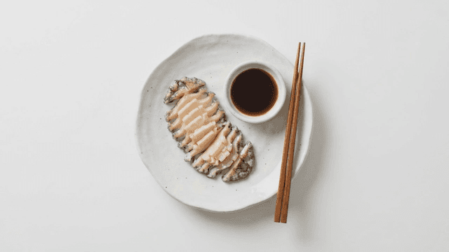 Sliced abalone with soy sauce on a plate
