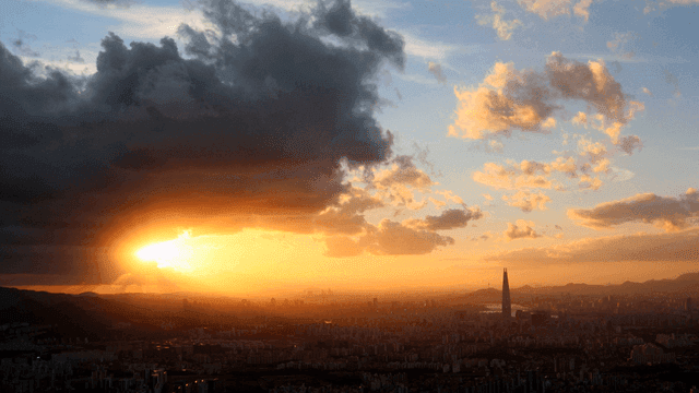 Sunset over a city skyline with clouds