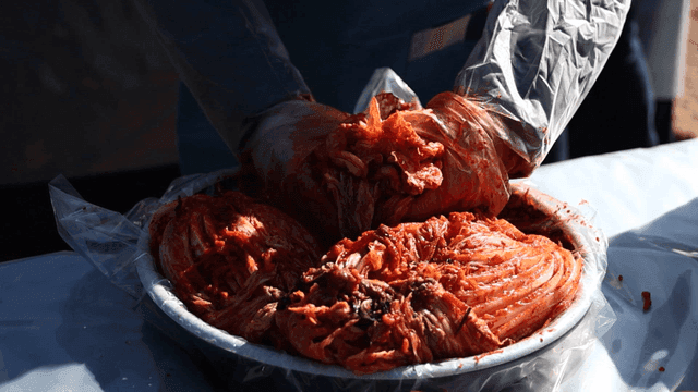 Person making kimchi in large bowl