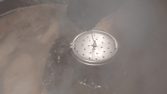 Metal broth strainer immersed in boiling broth